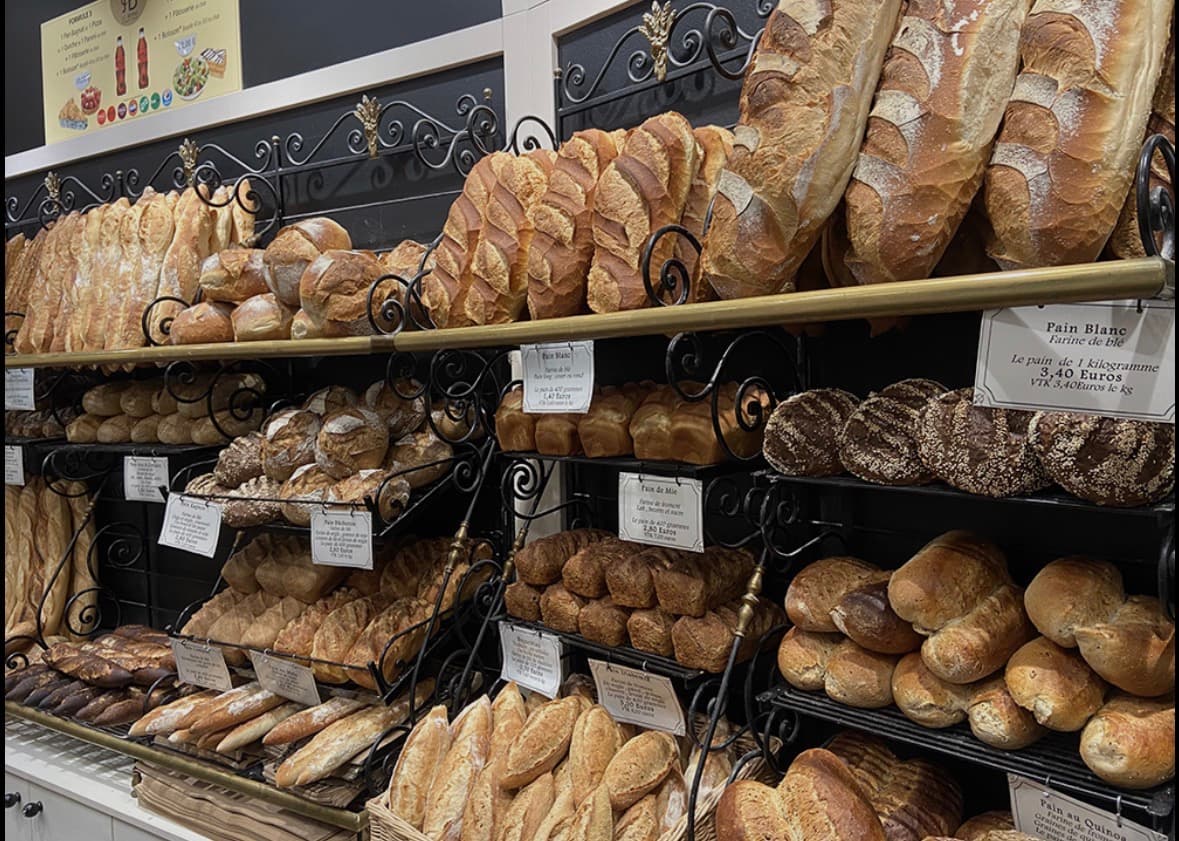 Étalage de boulangerie présentant une grande variété de pains artisanaux, baguettes et miches dorées.