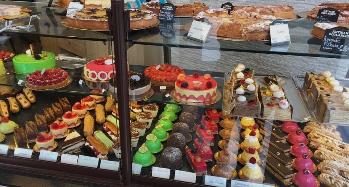 Vitrine de pâtisserie remplie de gâteaux colorés, tartes aux fruits et diverses pâtisseries artisanales.